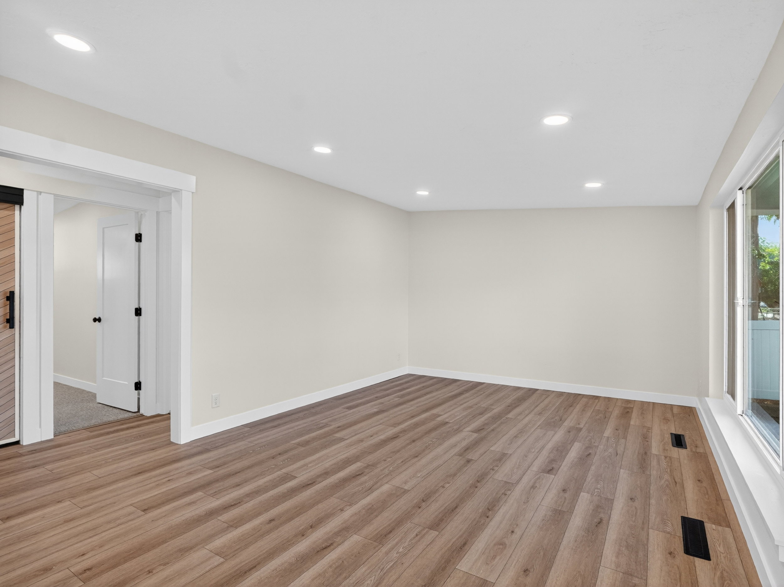 Bright interior space featuring wood-finish flooring, recessed lighting, white trim, and a barn door