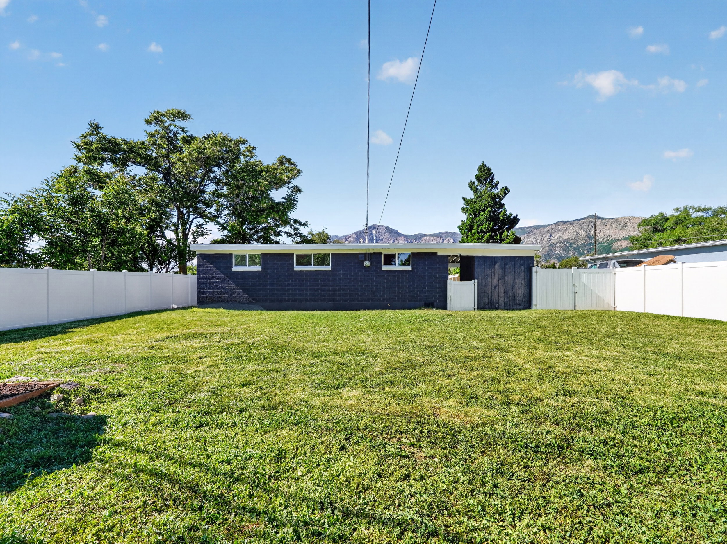 Expansive green lawn with a white privacy fence encompassing the backyard