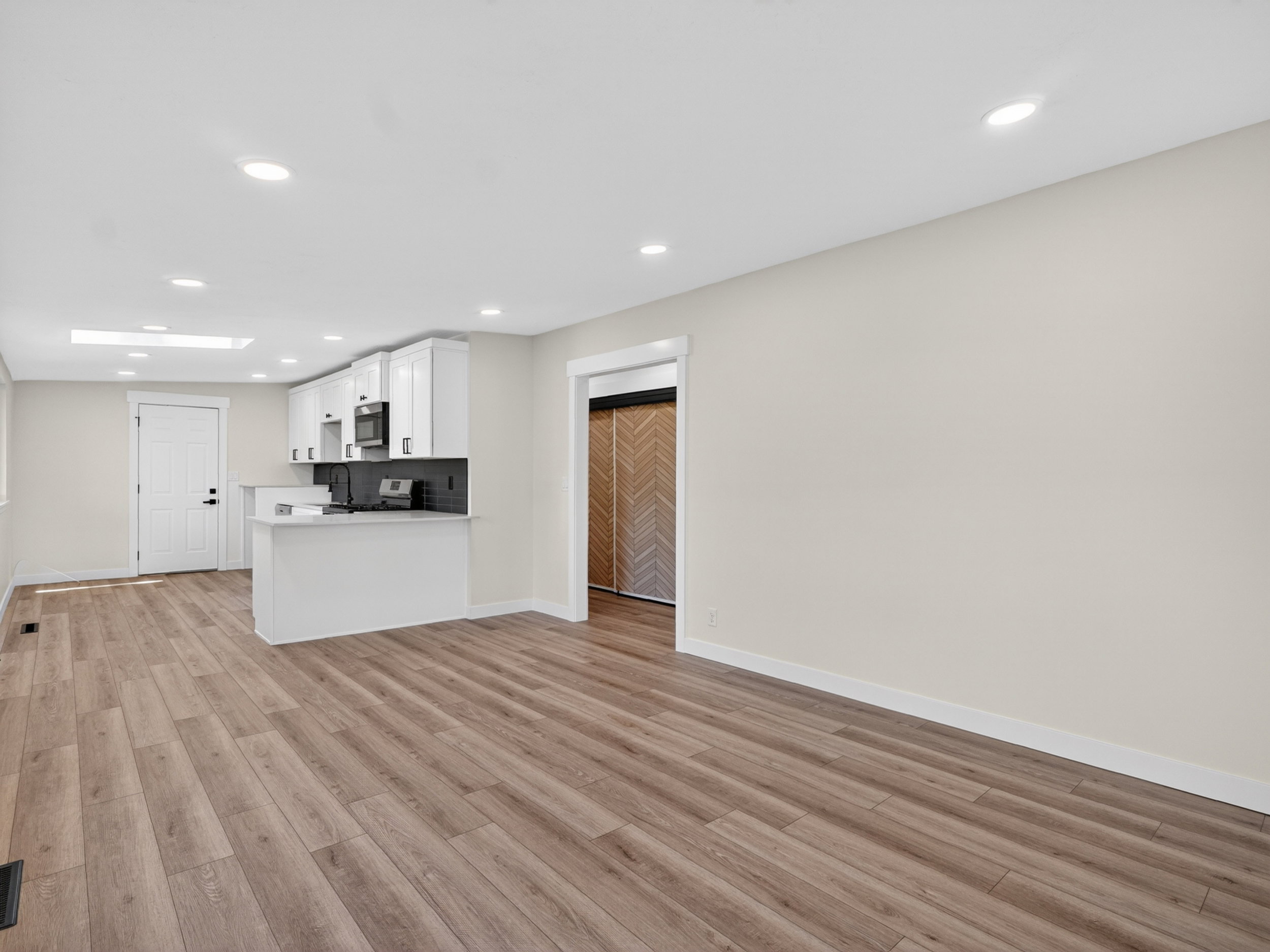 Open-concept interior featuring wood-finish flooring, recessed lighting, and a kitchen island with seating