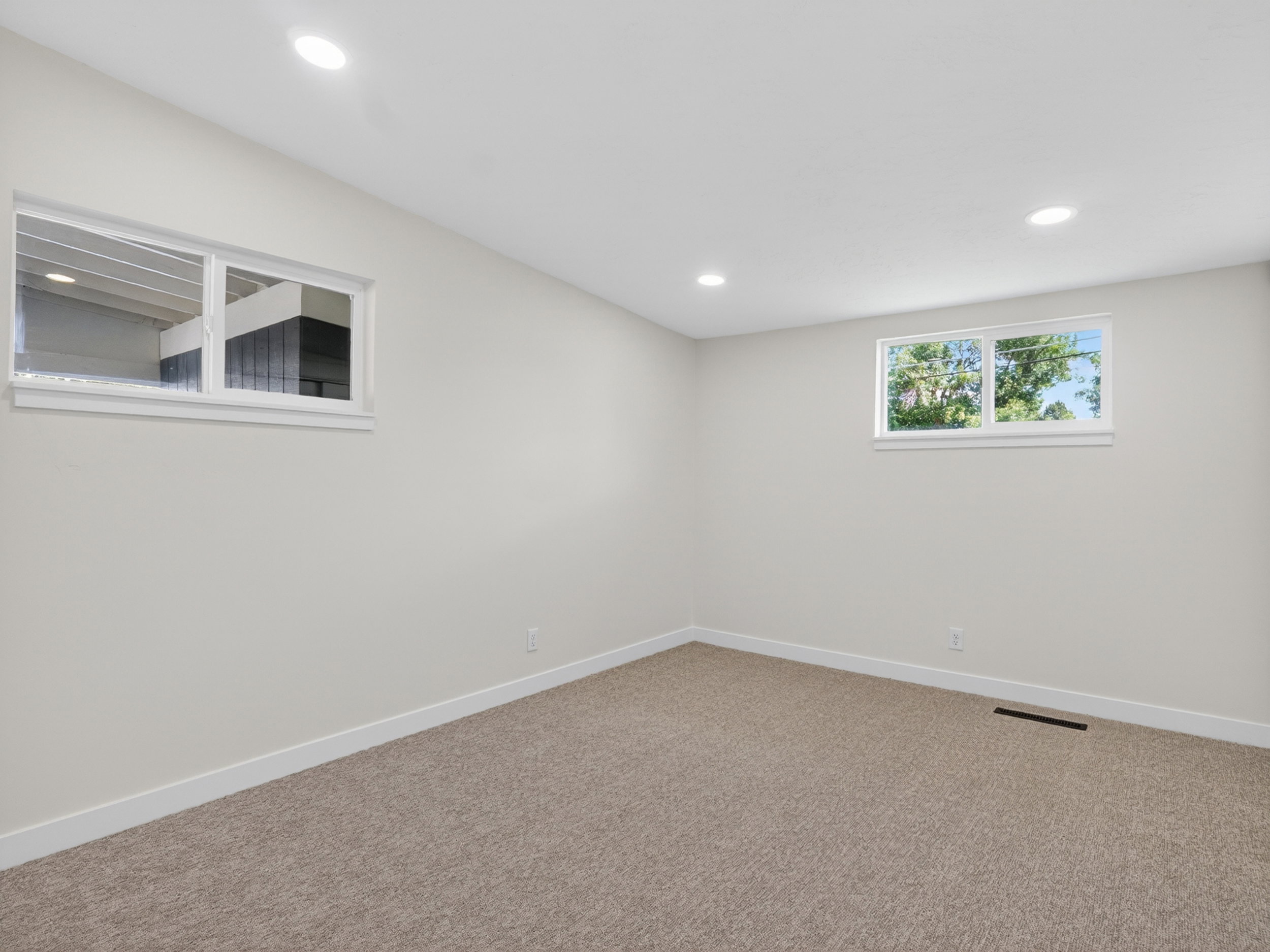 Neutral tone walls with white trim, recessed lighting, and light brown carpet