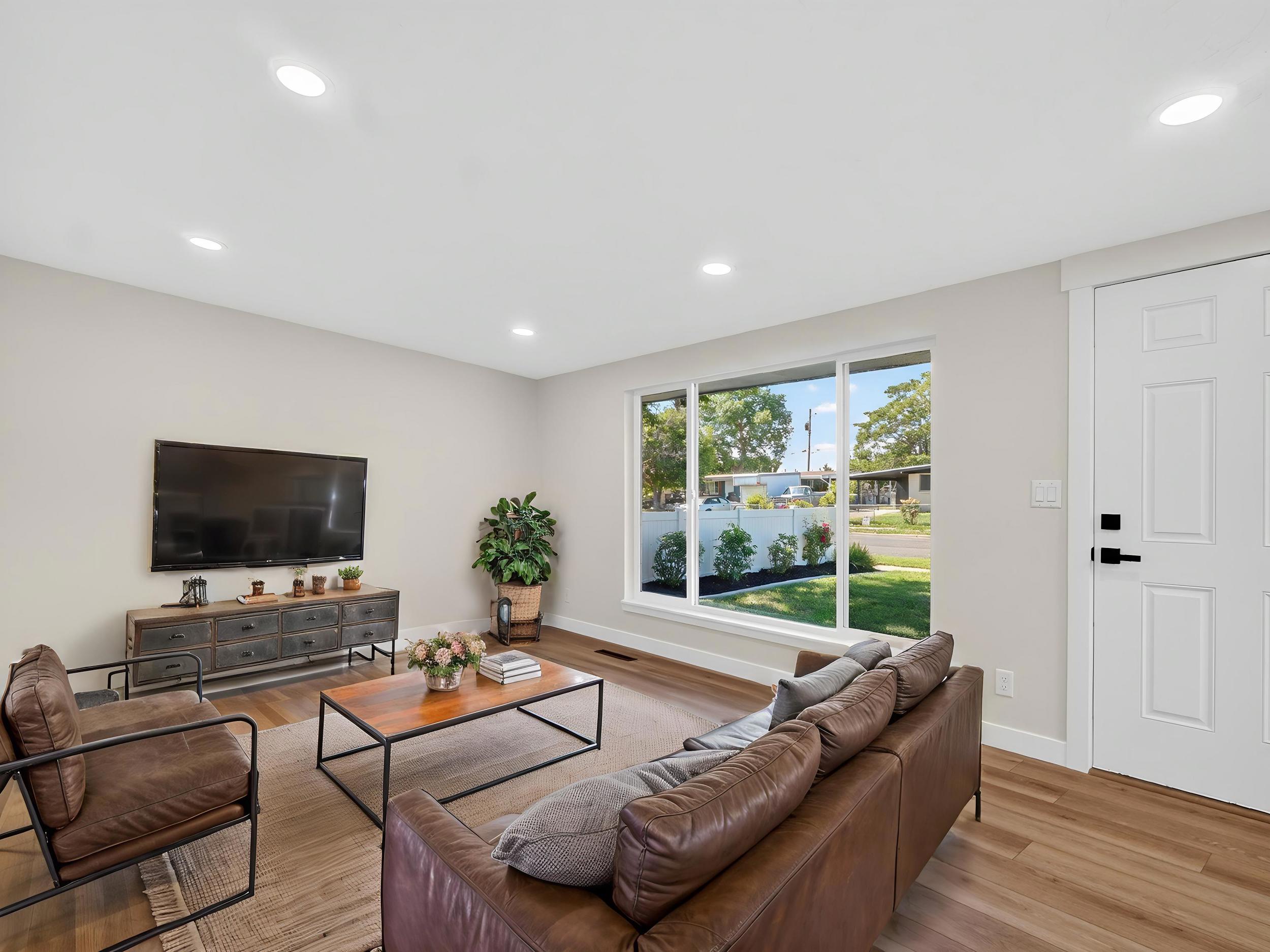 *Virtually Staged* Light-filled interior featuring wood-finish flooring, recessed lighting, and a large picture window