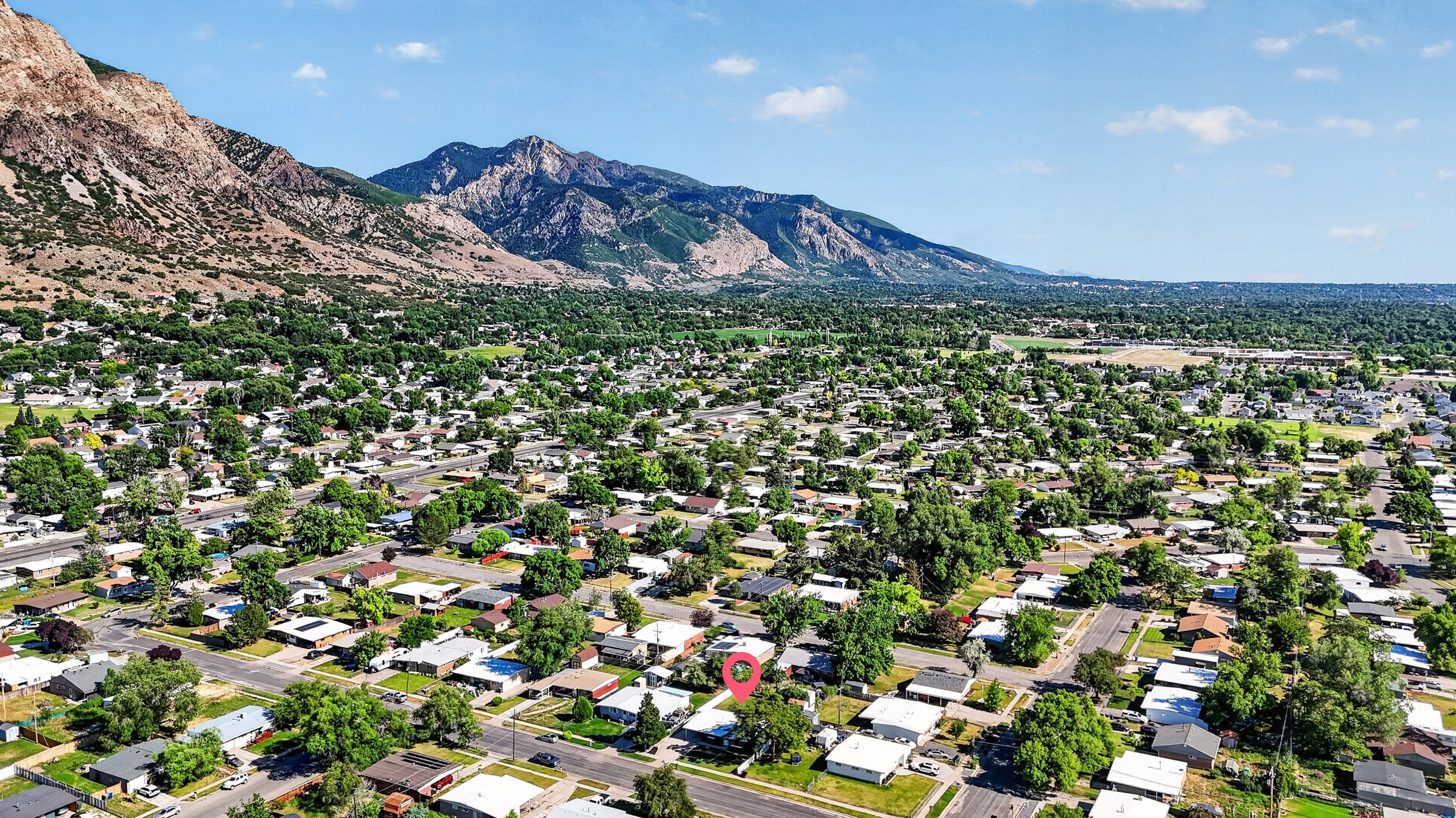 Residential neighborhood with mature trees, surrounded by mountain ranges