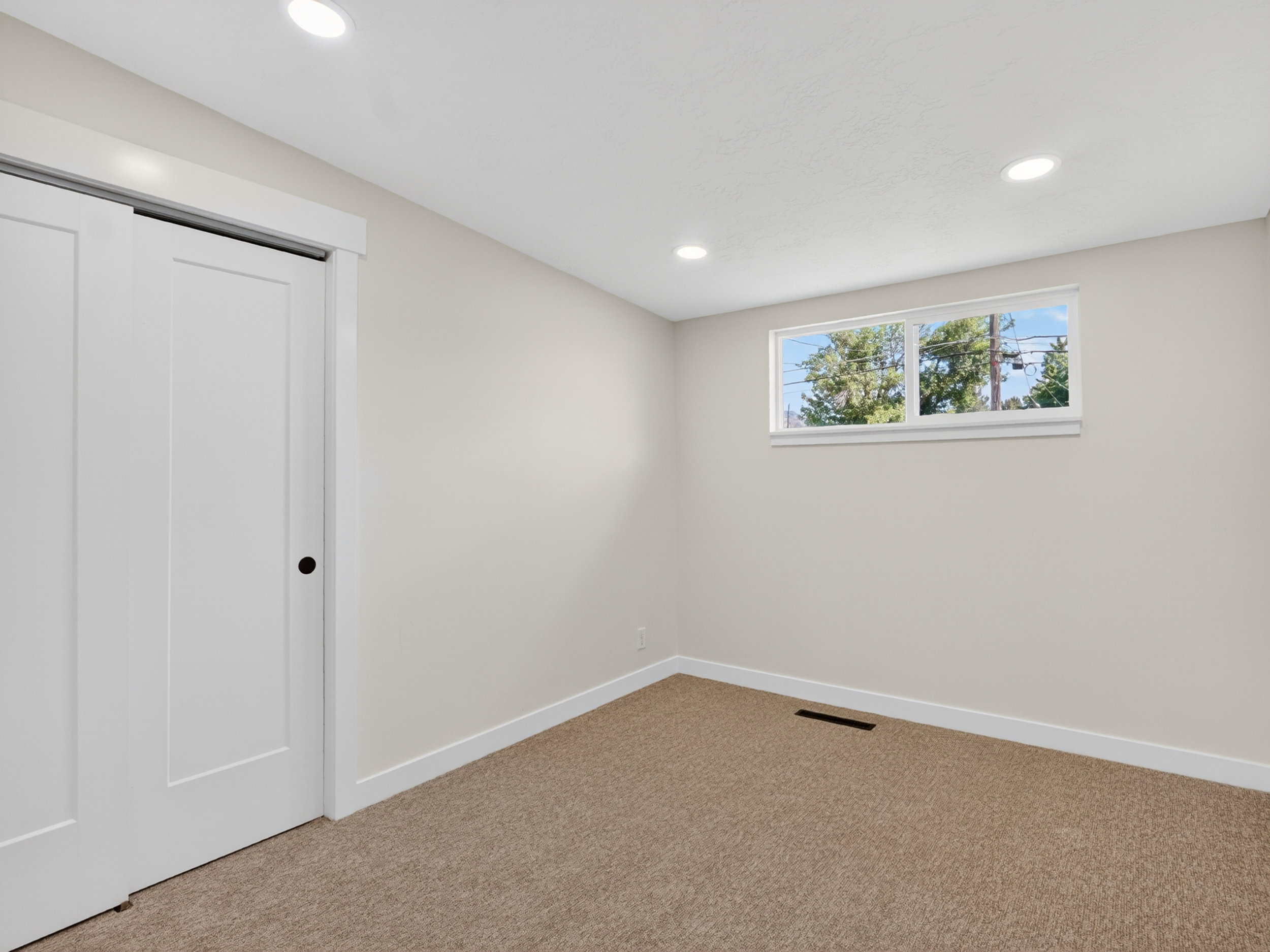 Neutral-toned room featuring light beige carpeting, white trim, and a window with white casing