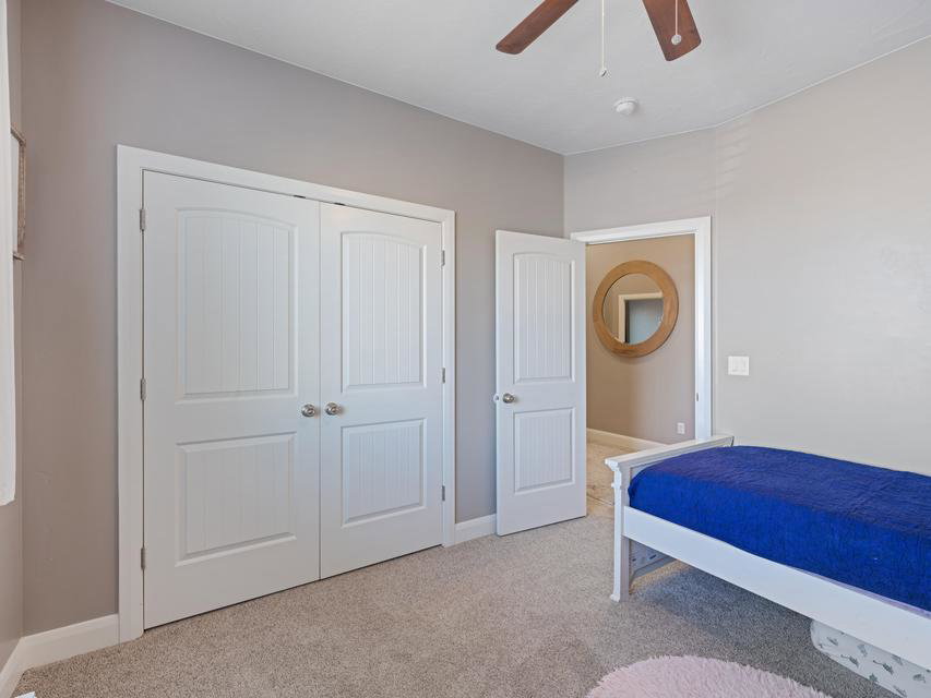 Bedroom featuring plush carpet flooring, neutral wall tones, white trim, and a ceiling fan with integrated lighting
