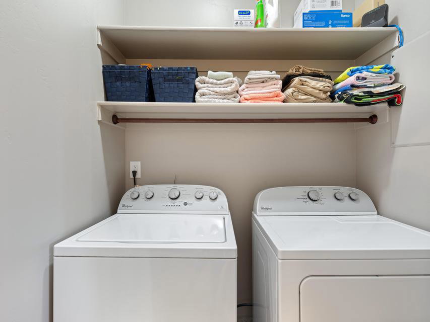 Laundry area featuring a built-in top shelf, an integrated hanging rod, and light neutral wall finishes