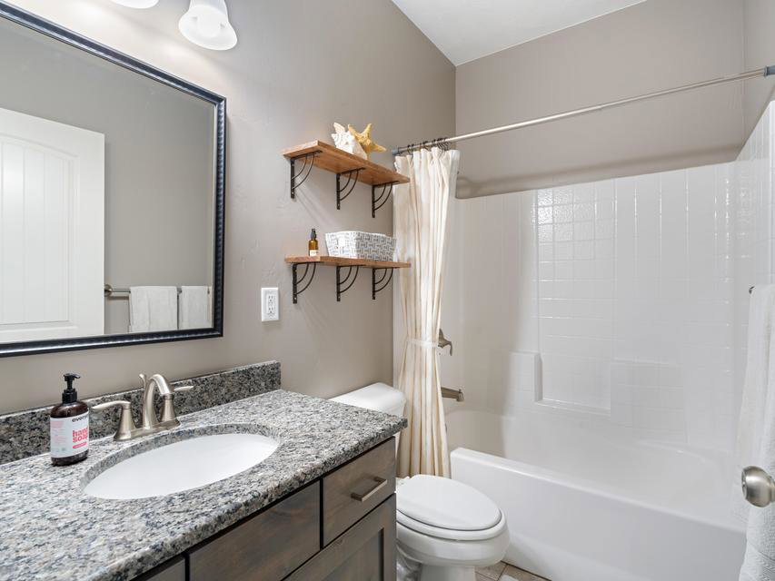 Bathroom vanity featuring a granite countertop with an oval undermount sink, brushed nickel faucet, and wood-finish cabinetry
