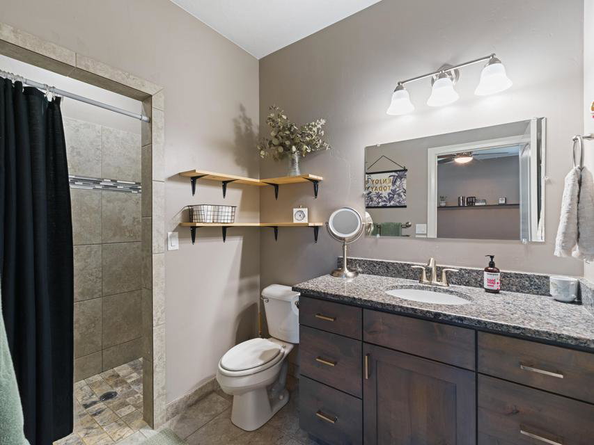 Bathroom featuring a dark wood-finish vanity with a granite countertop and undermount sink