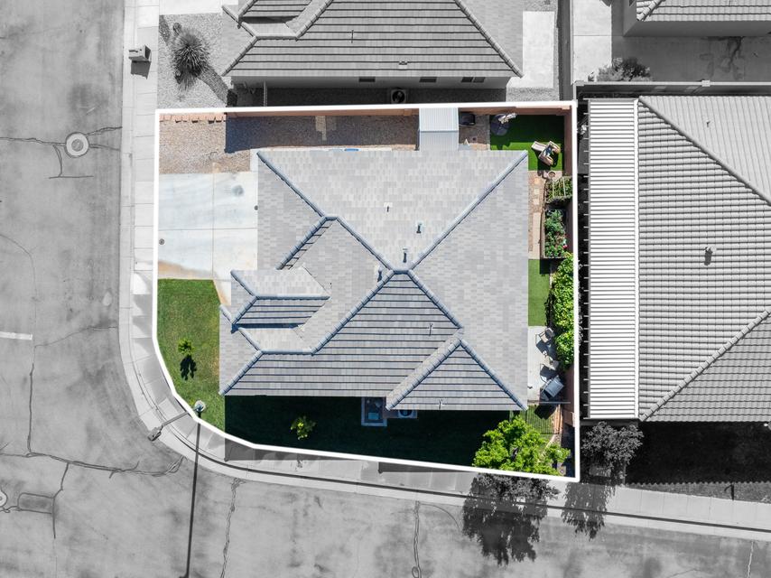 Property featuring a hip roof design, front lawn, concrete driveway, and side yard with artificial turf and planted garden beds