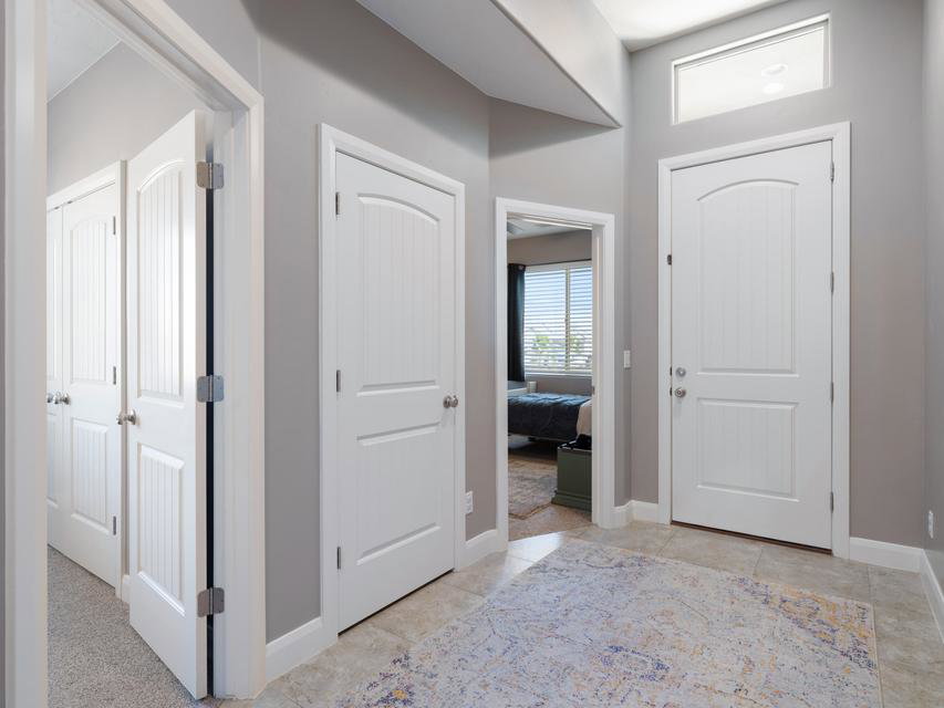 Entryway featuring tile flooring, white arched panel doors, and a transom window