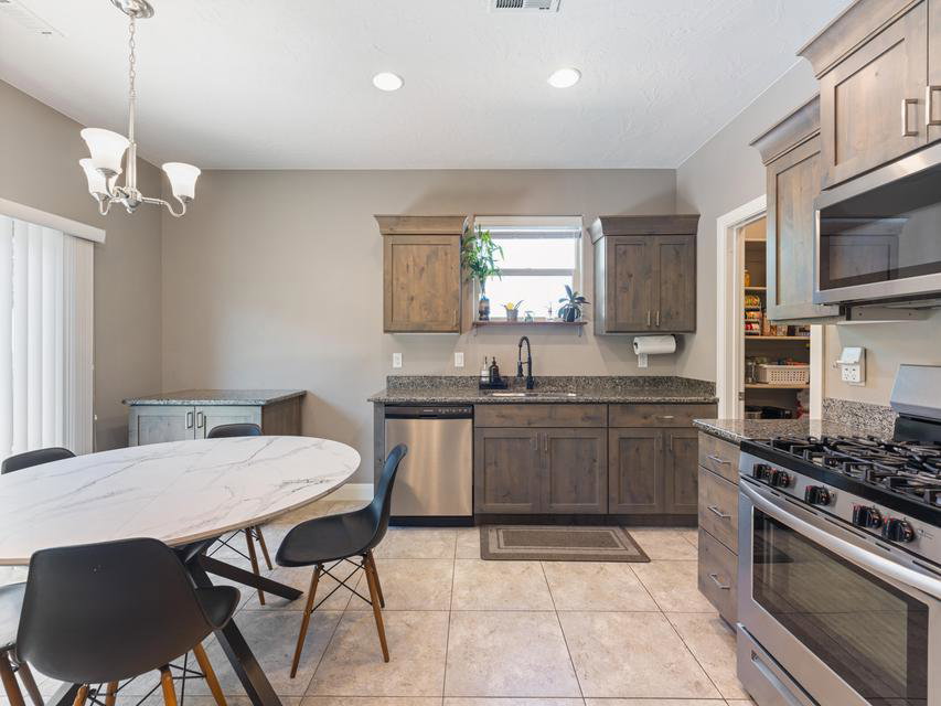 Kitchen featuring wood-finish cabinetry, granite countertops, tile flooring, and stainless steel appliances