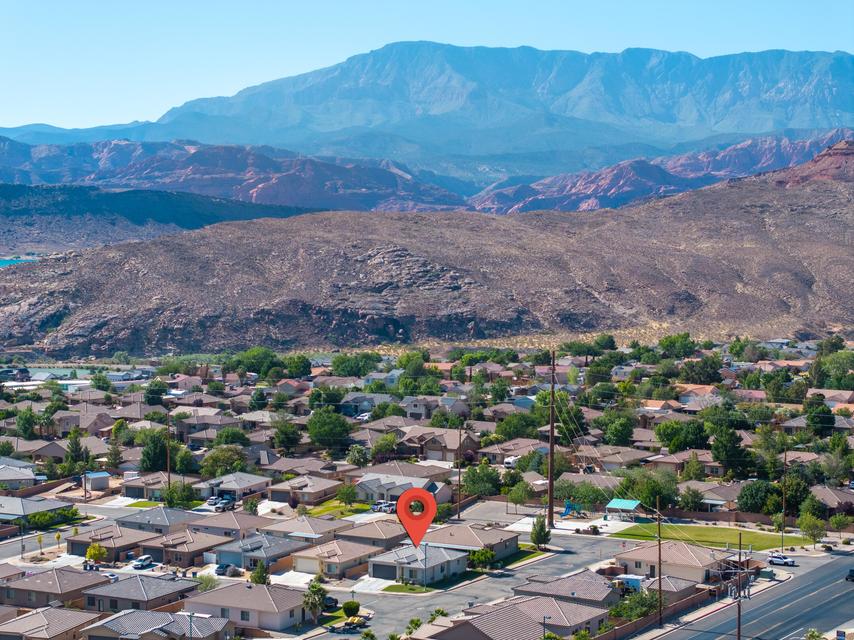 Residential neighborhood featuring single-story homes with pitched roofs, surrounded by mature trees and desert landscaping