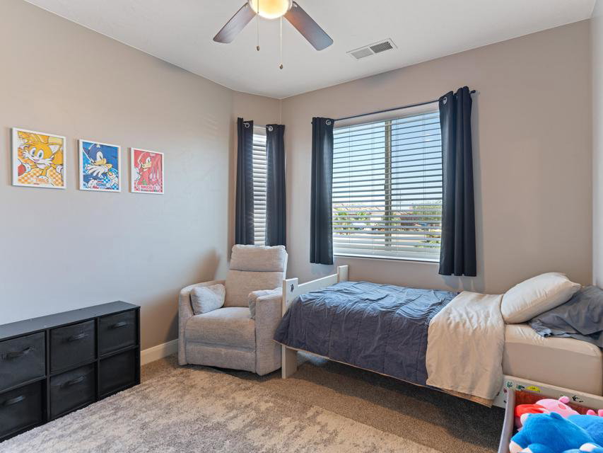 Bedroom featuring a ceiling fan, neutral wall color, and a window with horizontal blinds and dark curtains