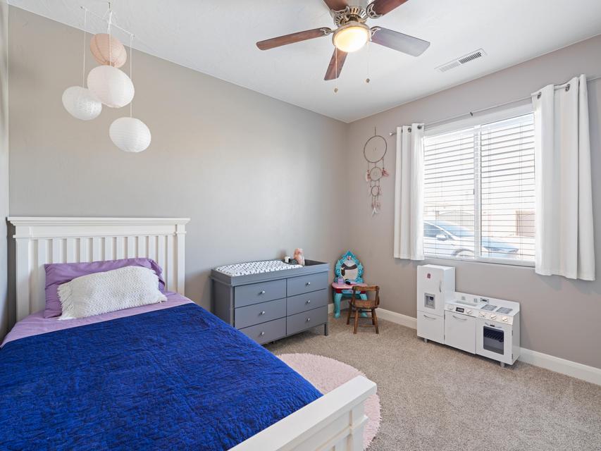 Carpeted room featuring a ceiling fan with integrated lighting, a window with horizontal blinds, and neutral wall tones