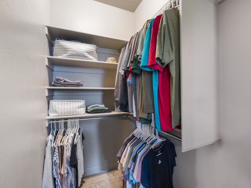 Walk-in closet featuring built-in shelving, multiple hanging rods, and neutral wall tones