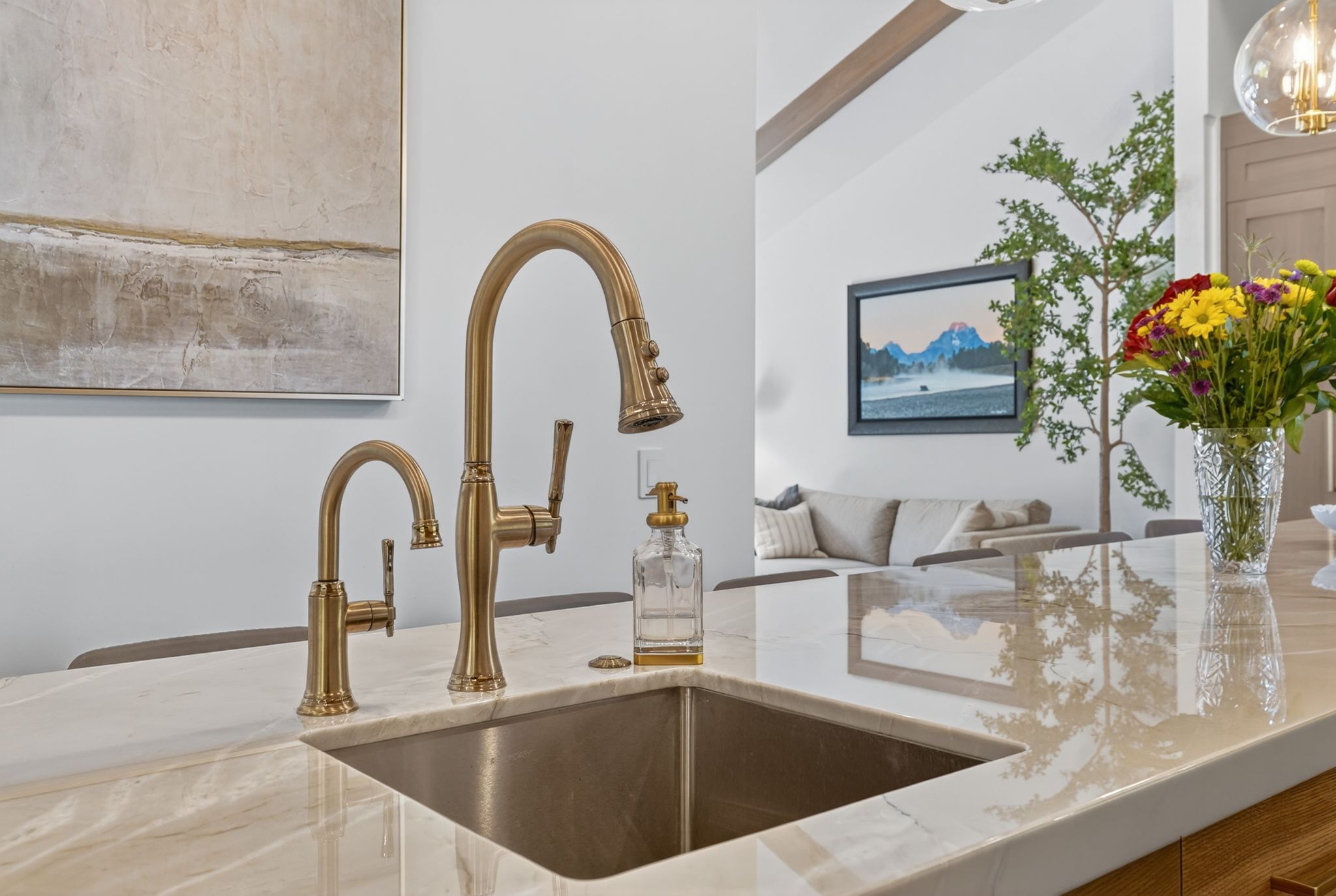 Kitchen island featuring a bronze-finish faucet set with an undermount sink and a polished stone countertop