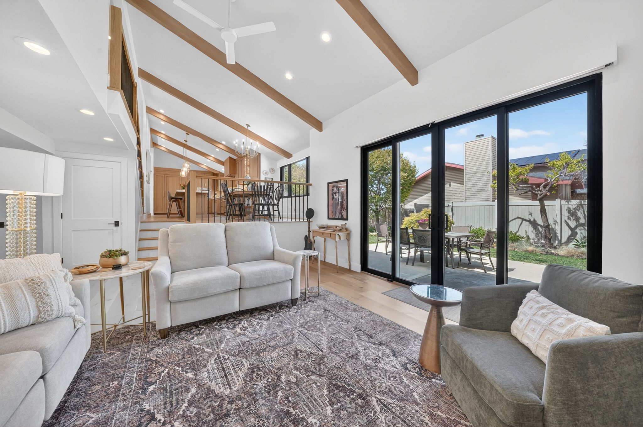 Vaulted ceilings with exposed wood beams, recessed lighting, and wood-finish flooring and automatic rolling shades