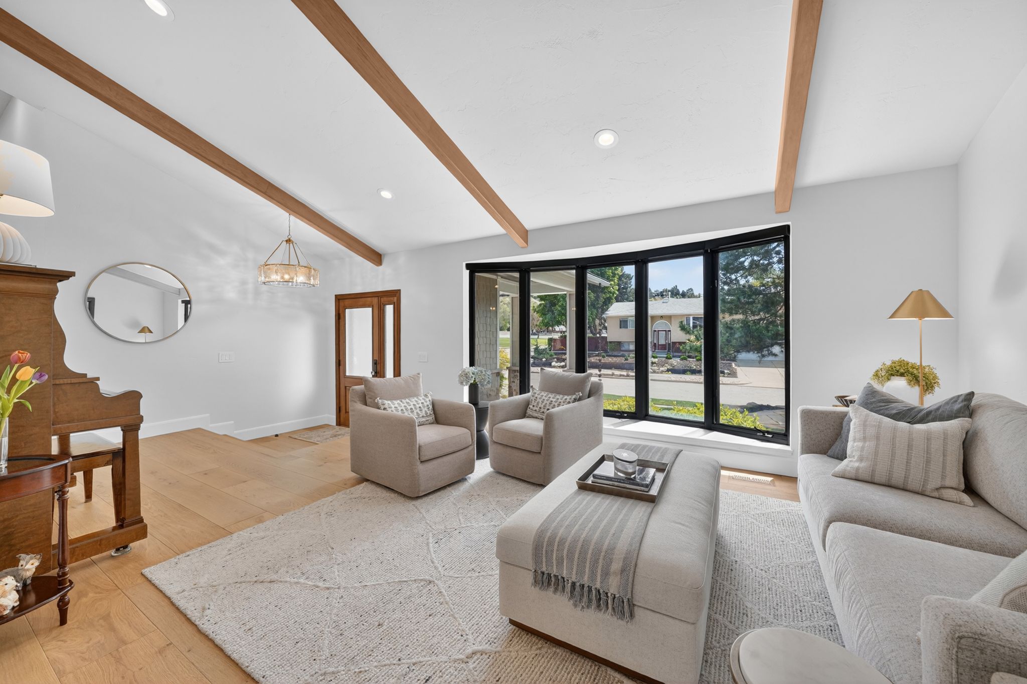 Vaulted ceilings with exposed wood beams define this living area, complemented by recessed lighting and a contemporary chandelier