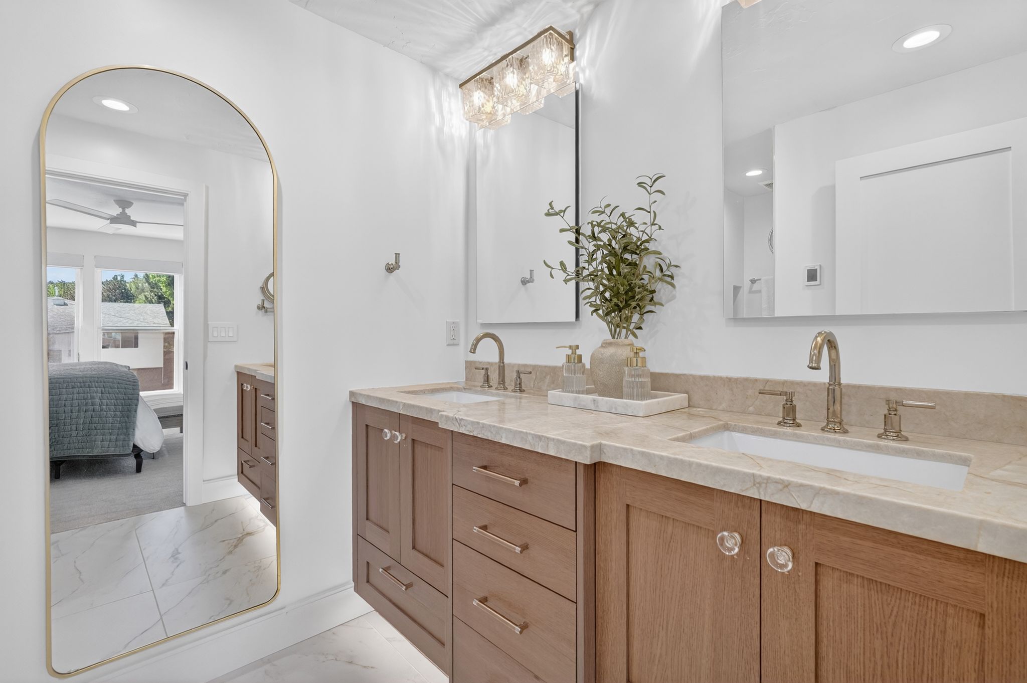 Dual vanity featuring light wood cabinetry, integrated sinks, and brass-finish hardware