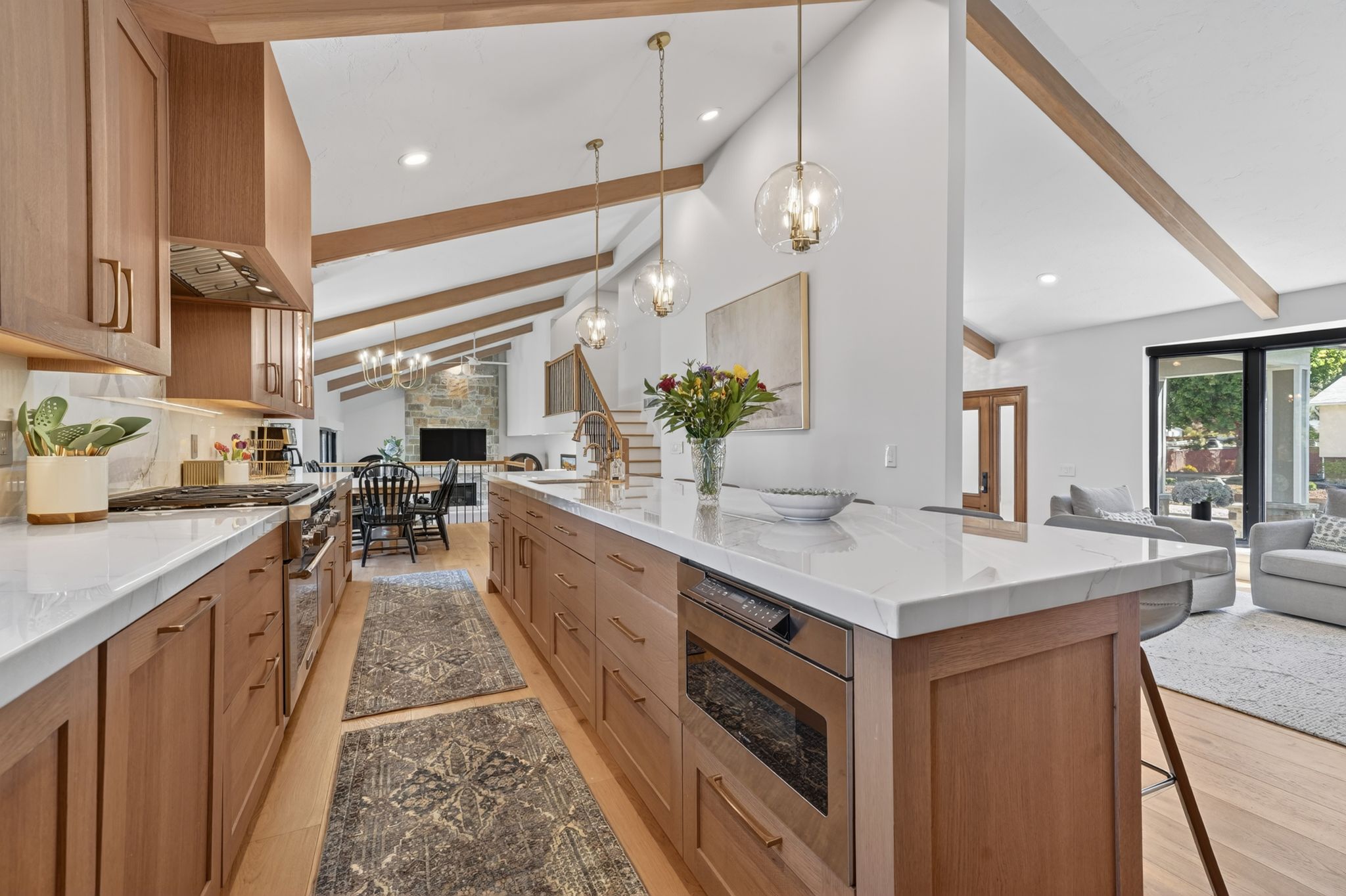 Gourmet kitchen with sleek wood-finish cabinetry, white  stone countertops, and a modern appliance suite