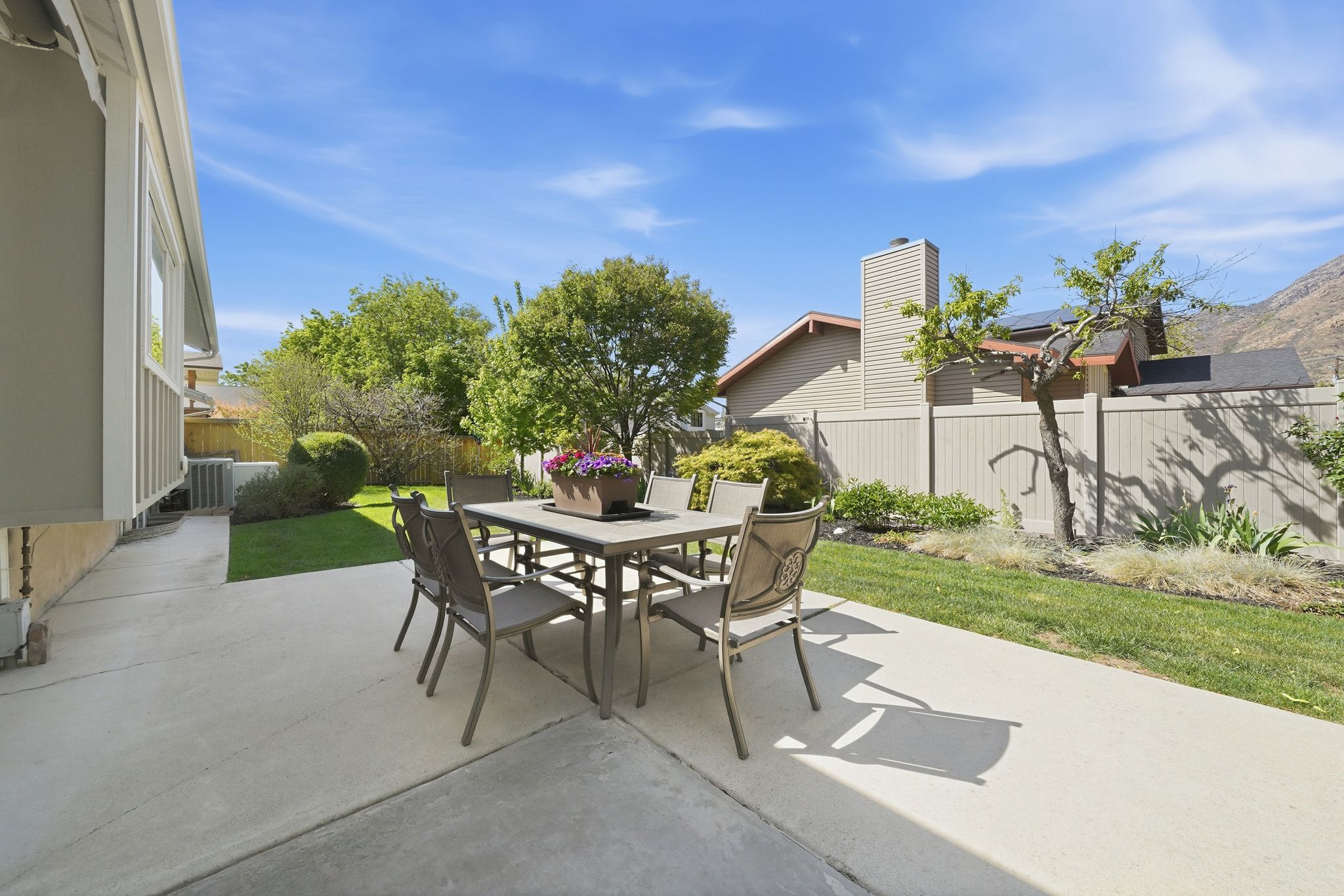 Expansive concrete patio with a manicured lawn and mature landscaping