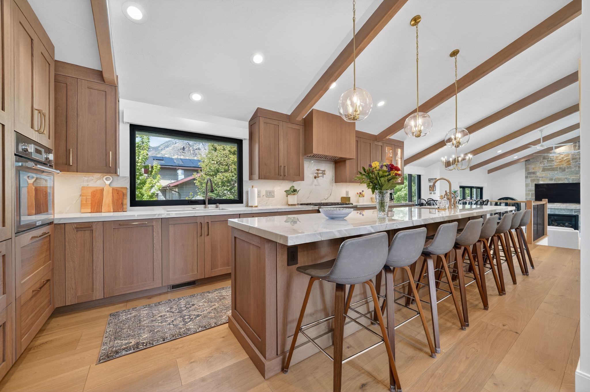 Expansive kitchen featuring light wood cabinetry, recessed lighting, wood-finish flooring, a large island with seating, and a window with mountain scenery