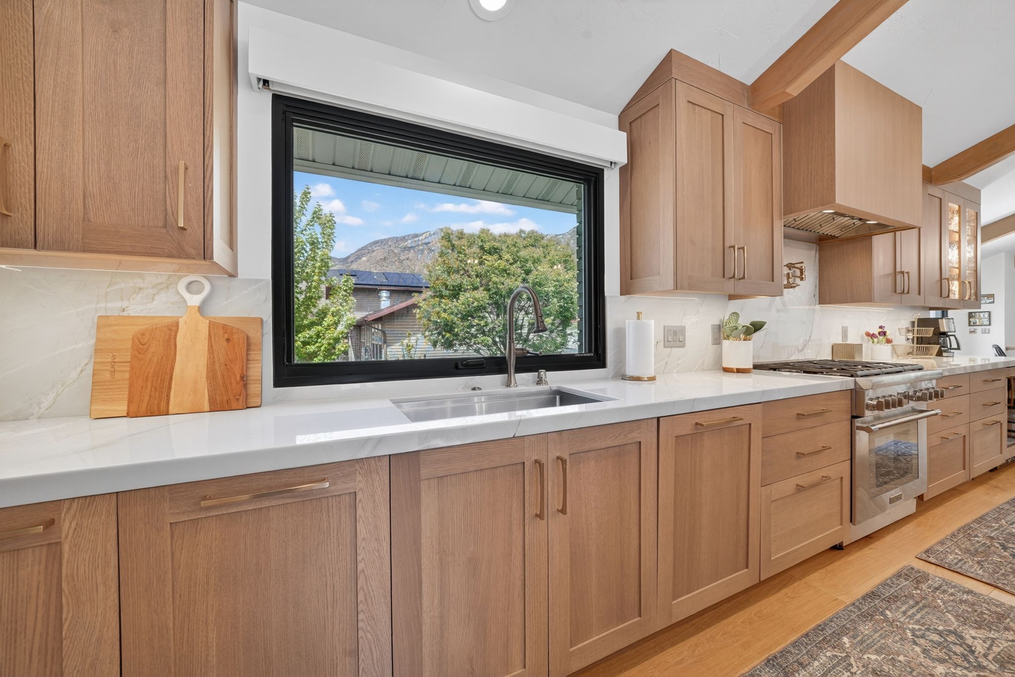 Kitchen featuring light wood-finish cabinetry, white stone countertops, and a full-height backsplash