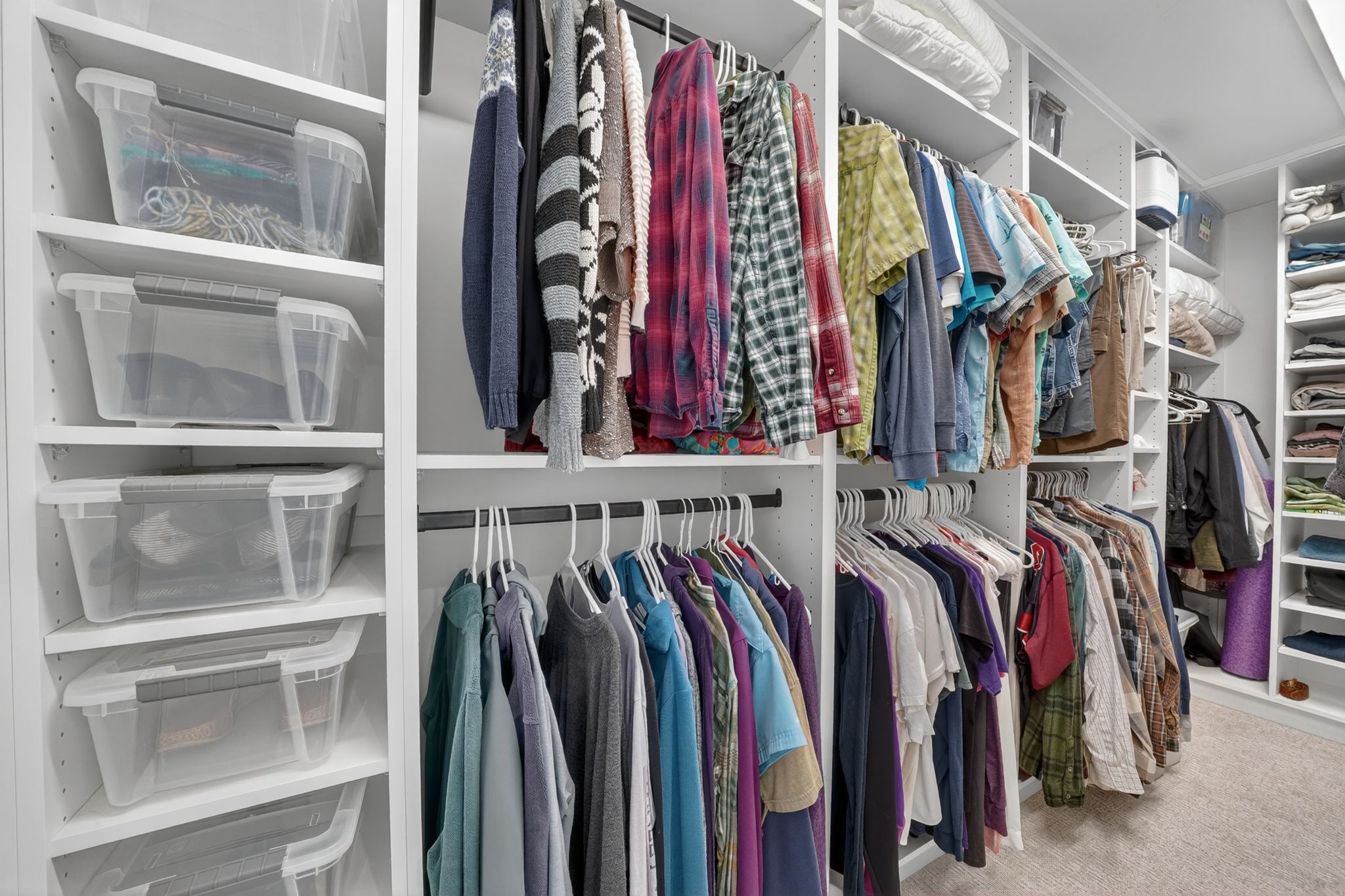 Custom closet system featuring white shelving, multiple hanging rods, and integrated storage compartments