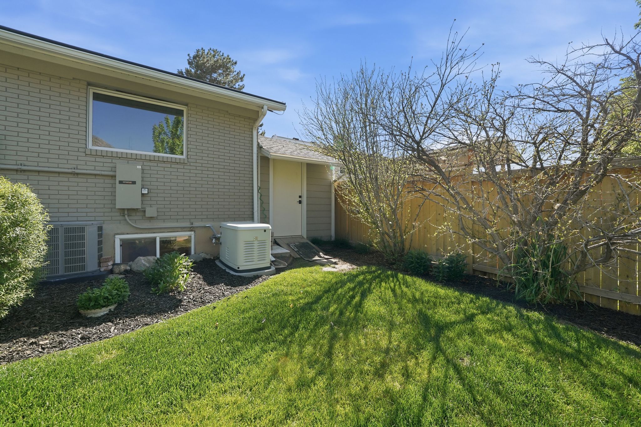 Lush green lawn with mature landscaping and privacy fence