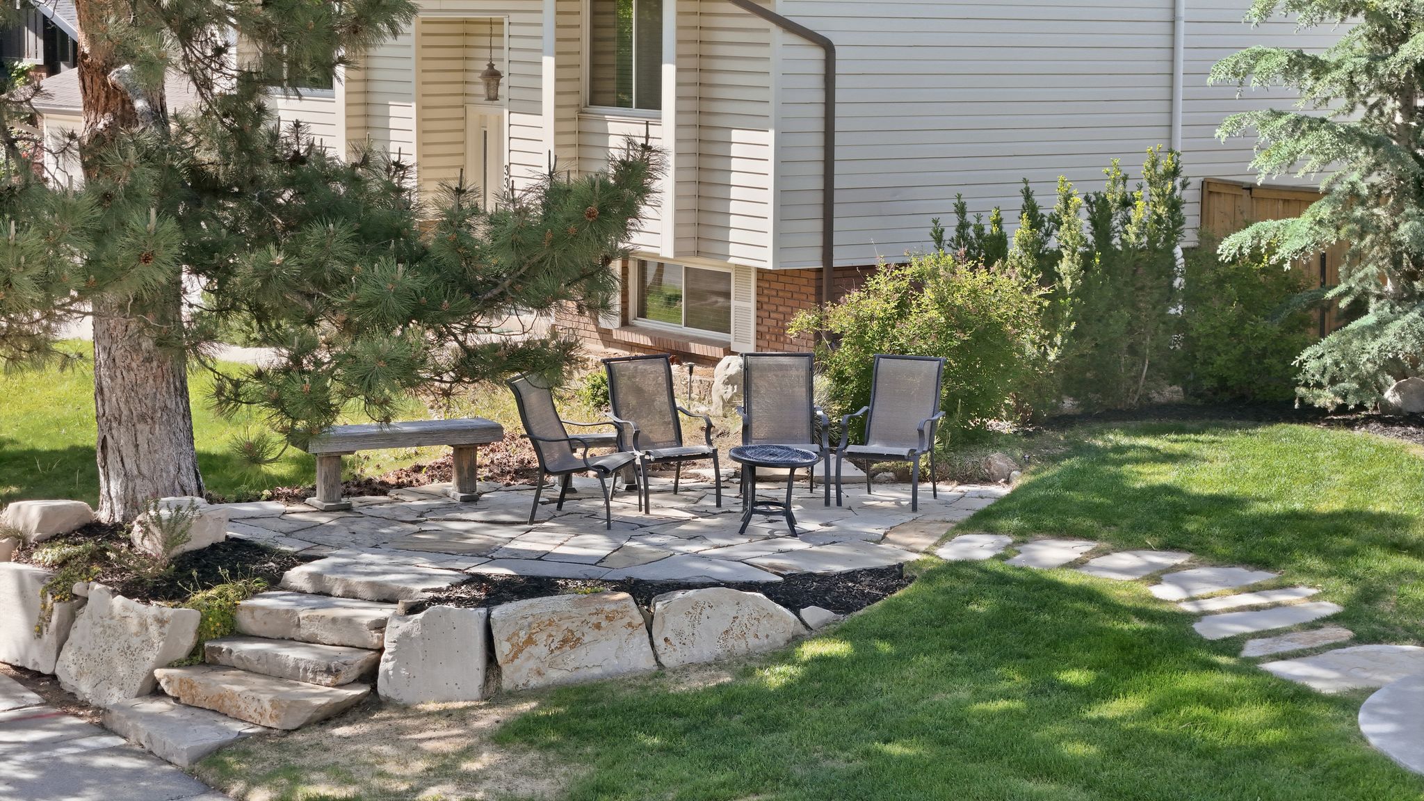 Front yard  flagstone patio, stone retaining walls, a stone pathway, and mature landscaping