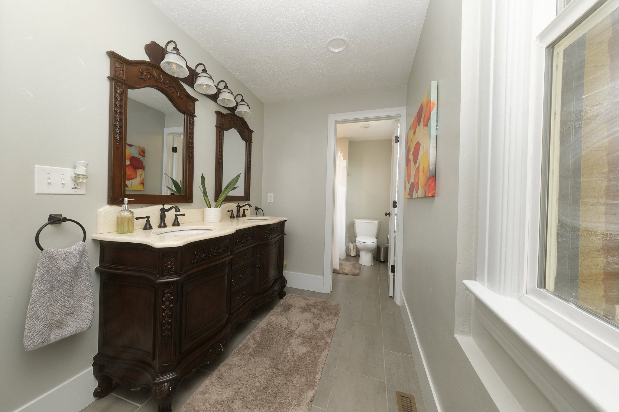 Double vanity featuring ornate dark wood cabinetry, dual undermount sinks, and stone-finish countertops