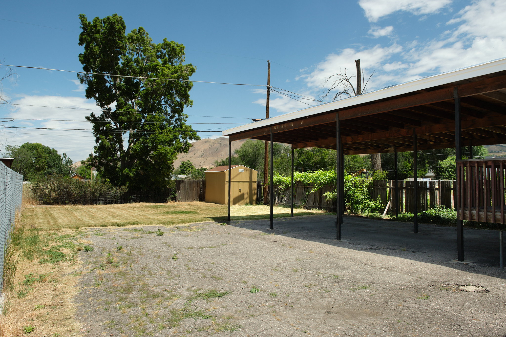 Expansive paved carport with a wooden deck extension