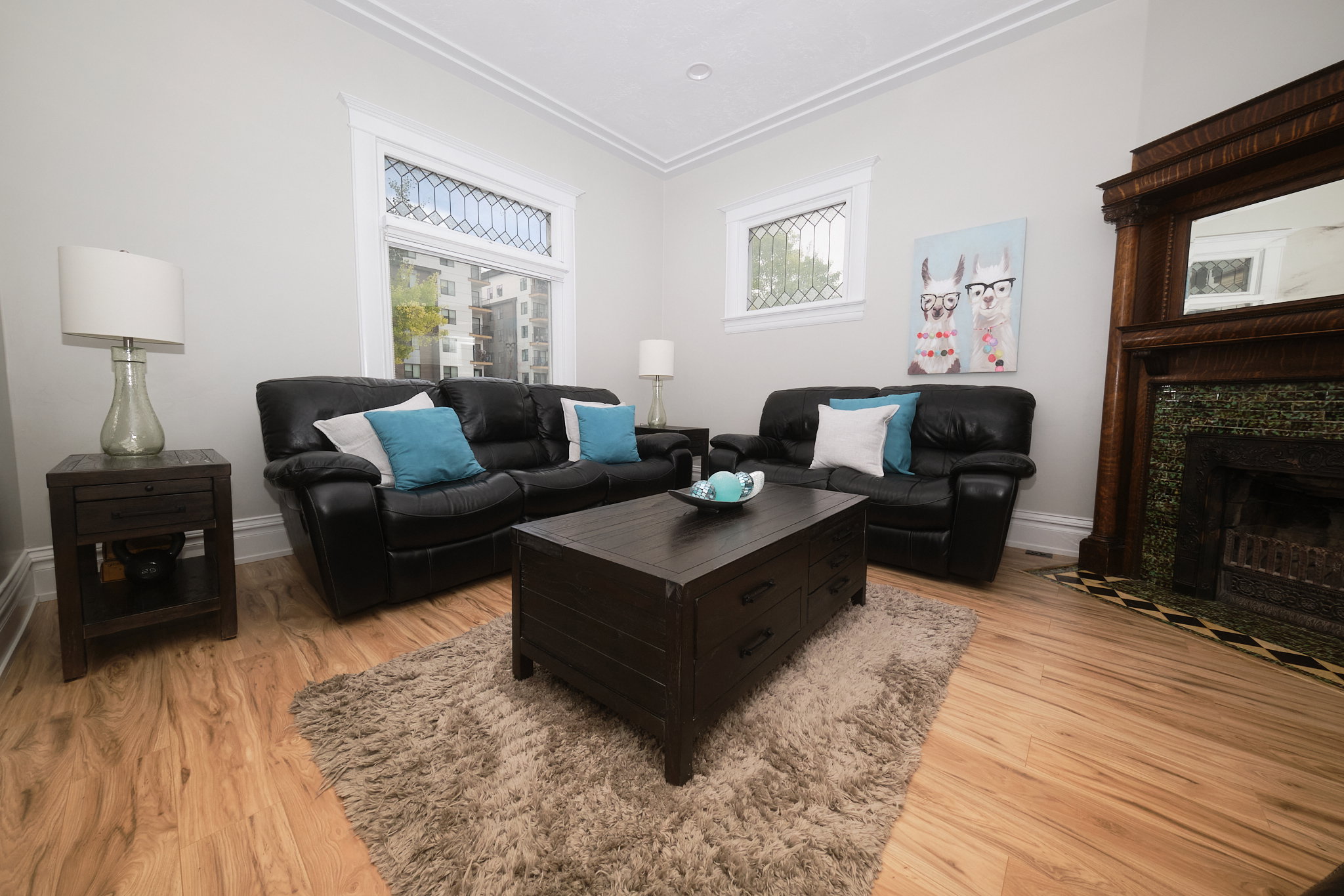Living area featuring wood-finish flooring, beautiful fireplace,  white crown molding, and windows with decorative grilles