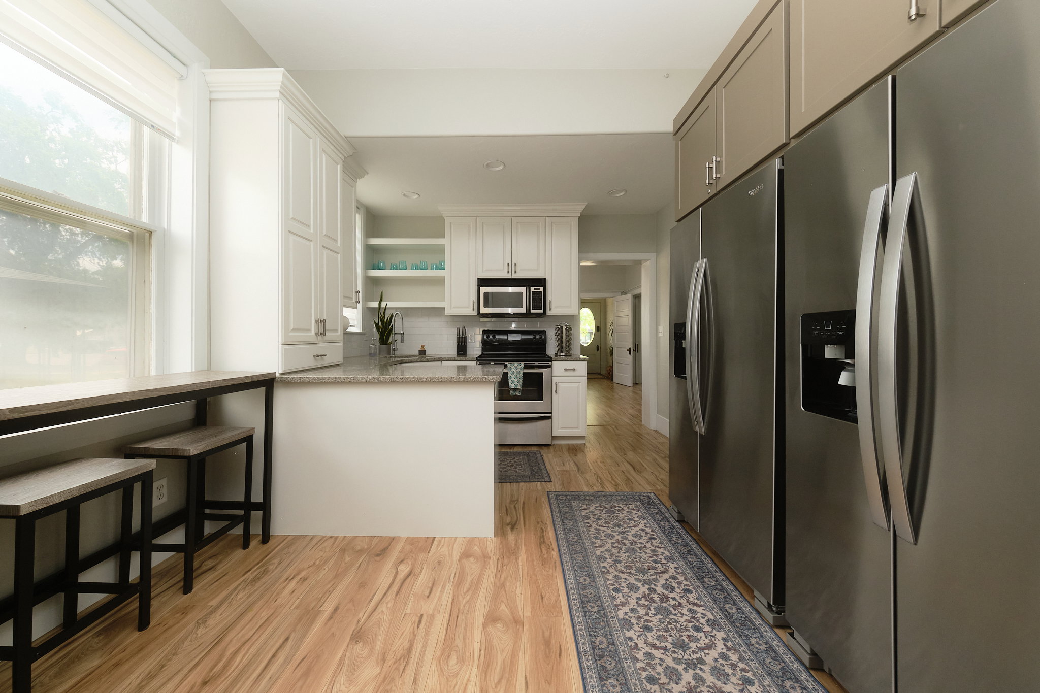 Open-concept kitchen featuring white cabinetry with crown molding, a granite-finish countertop, and a built-in breakfast bar