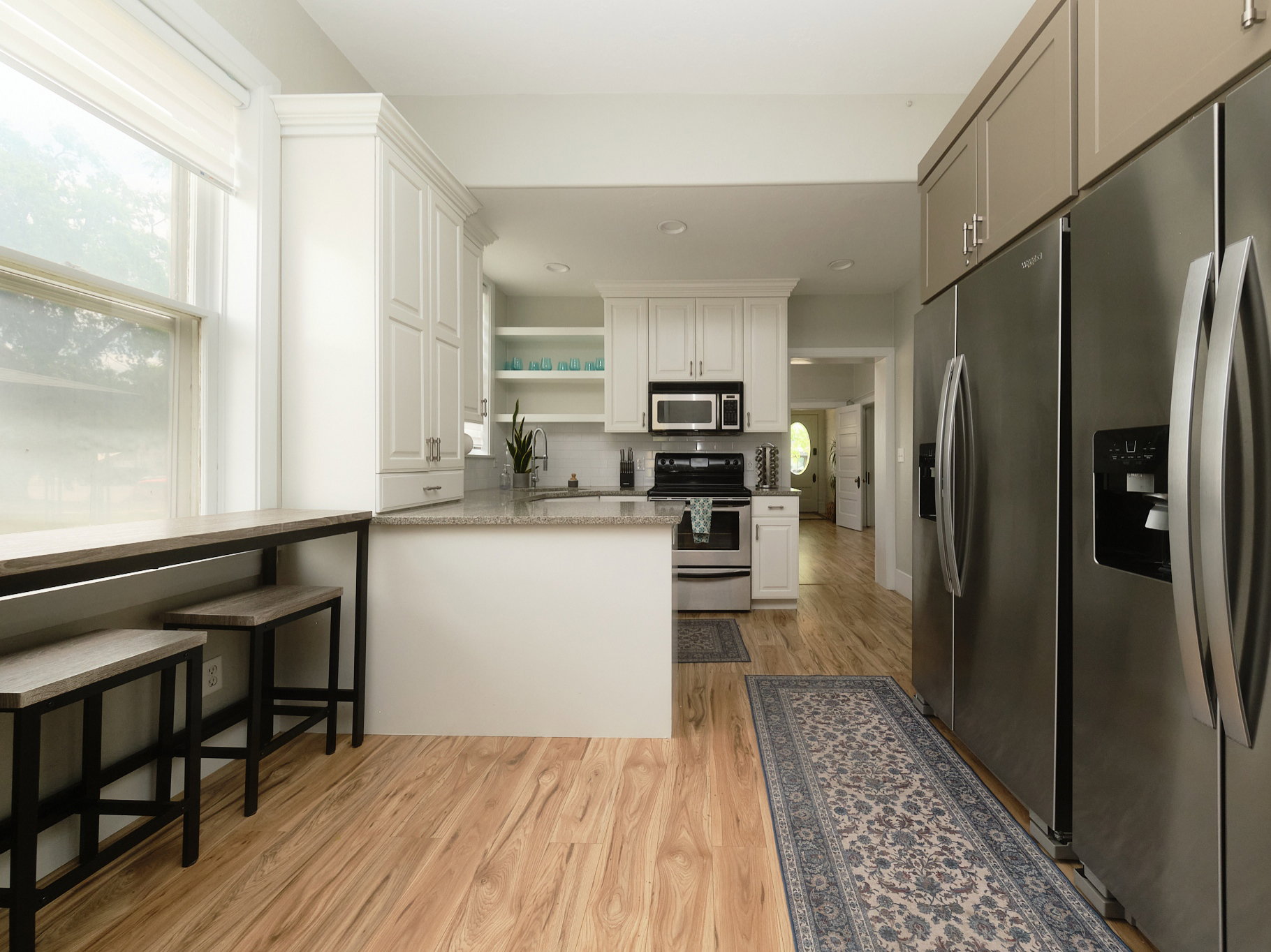 Open-concept kitchen featuring white cabinetry with crown molding, a granite-finish countertop, and a built-in breakfast bar