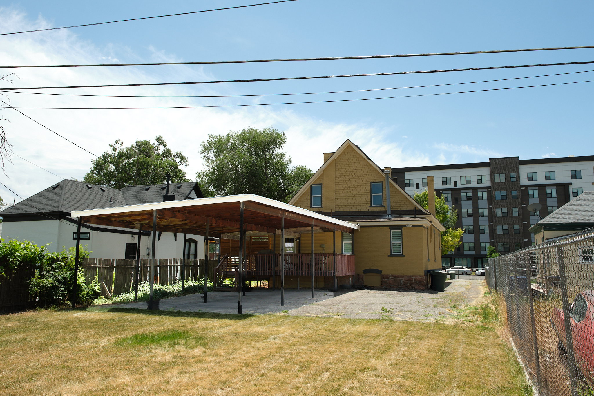 Rear exterior with yellow siding and a covered patio area. Covered parking for three vehicles.