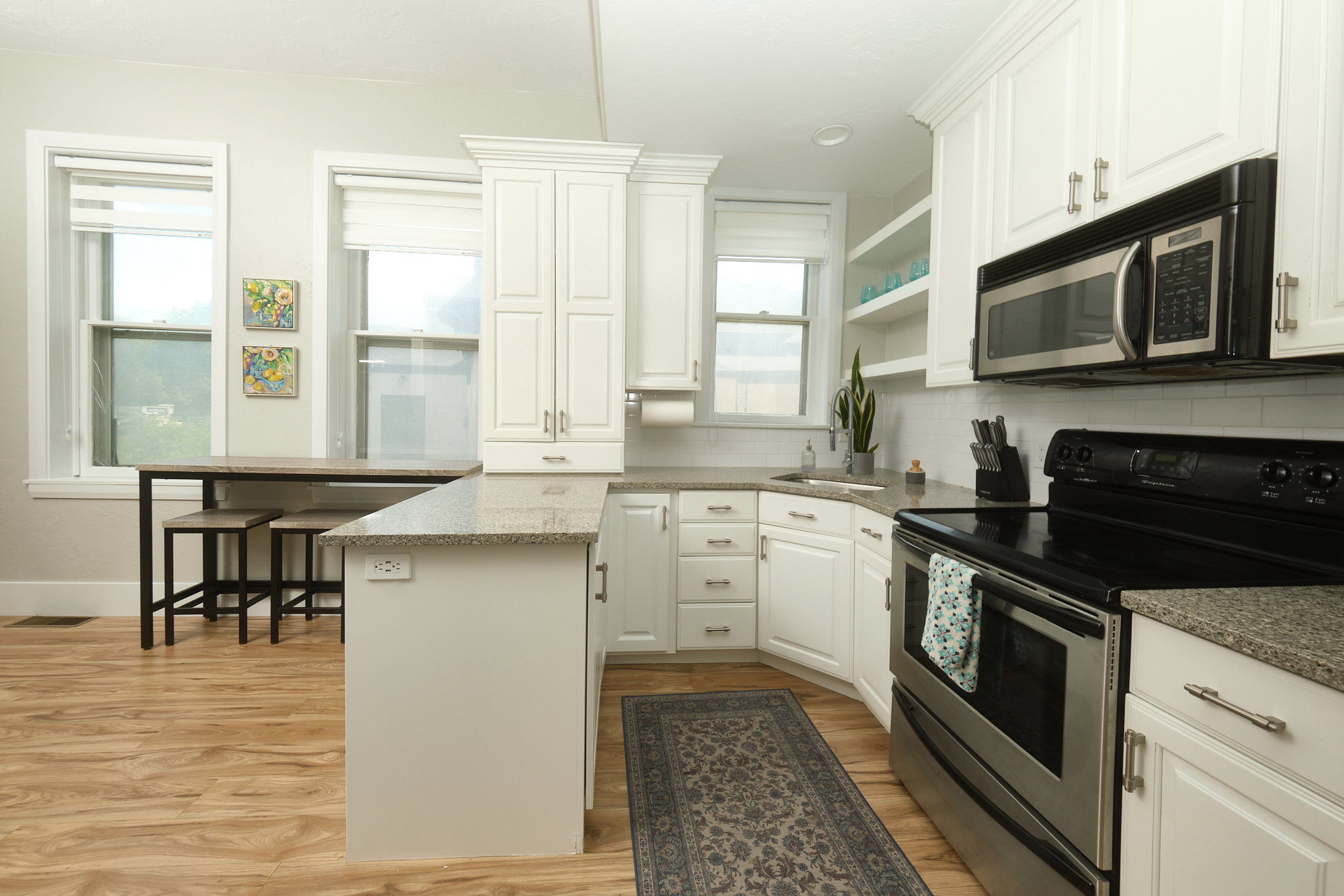 Contemporary kitchen with white cabinetry, stainless steel appliances, and light-toned wood-finish flooring