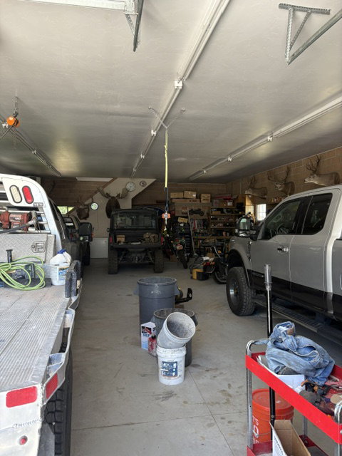 Spacious garage featuring a concrete floor, multiple fluorescent light fixtures, and exposed ceiling joists