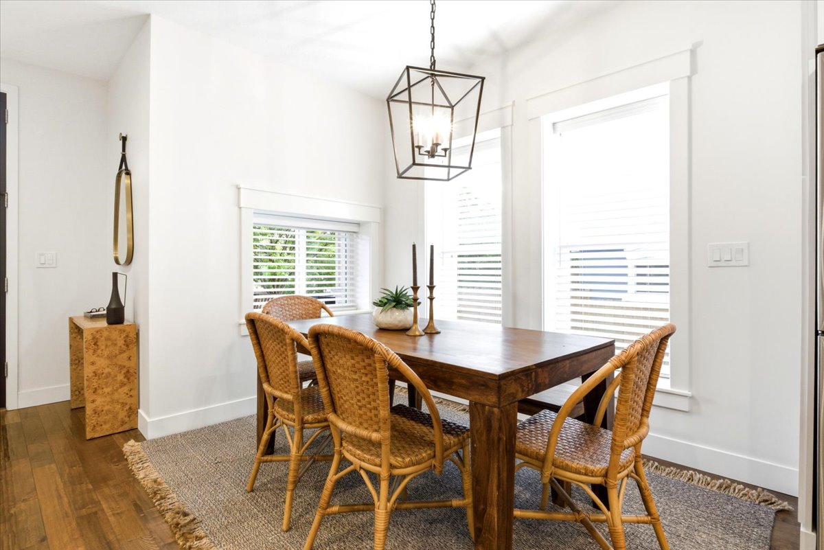 Dining area featuring a geometric chandelier, wood-finish flooring, two windows with blinds, and white trim