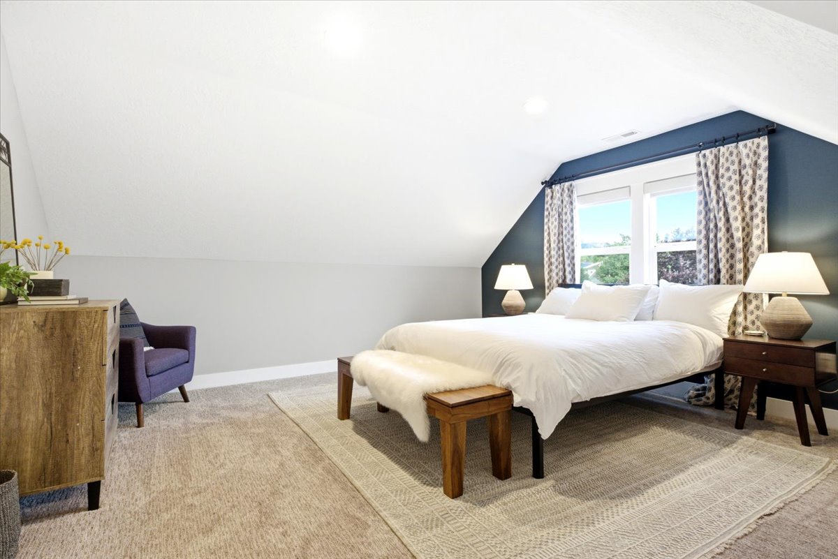 Carpeted bedroom featuring a vaulted ceiling, recessed lighting, and a large window with patterned drapes