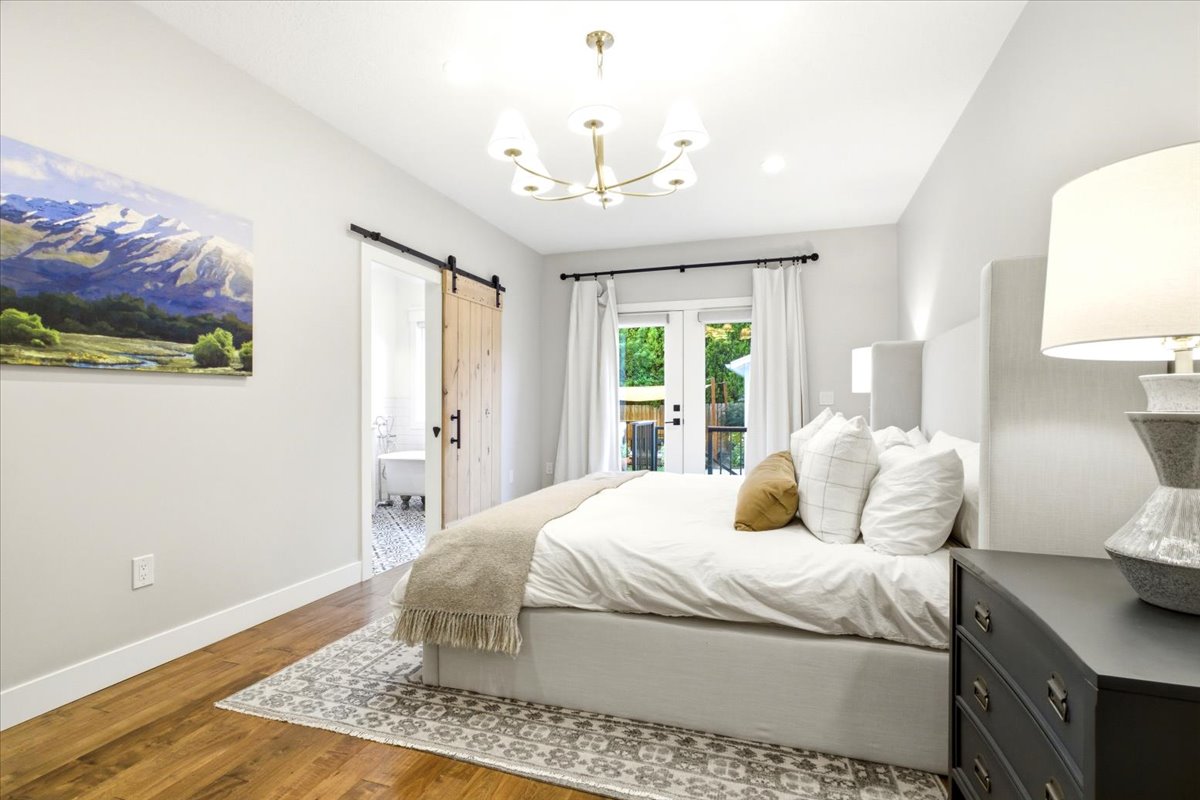 Bright bedroom featuring wood-finish flooring, a contemporary chandelier, recessed lighting, and white walls