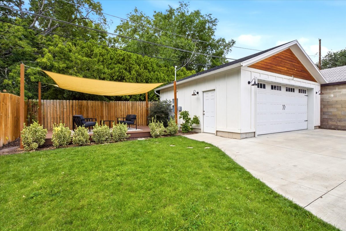 Spacious backyard featuring a manicured lawn, a privacy fence, and a dedicated patio space with a shade sail