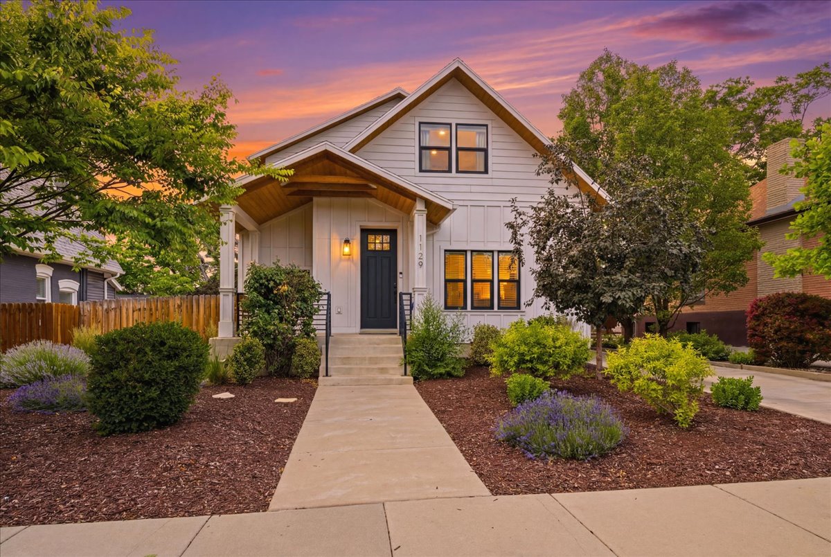 Modern farmhouse exterior with white board and batten siding, black-framed windows, a covered entry with wood-finish ceiling, and a dark entry door