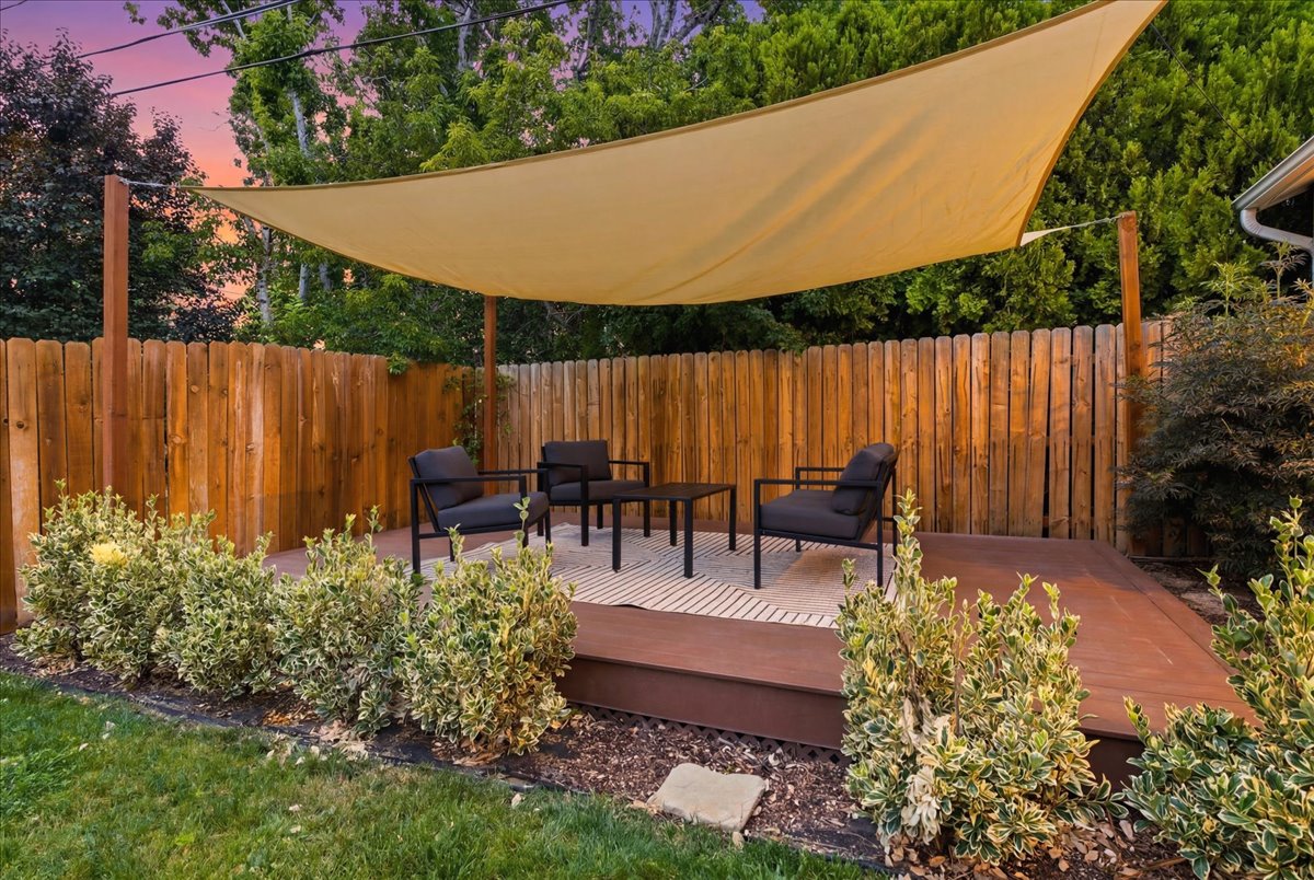 Backyard wood deck featuring a sun shade and privacy fence