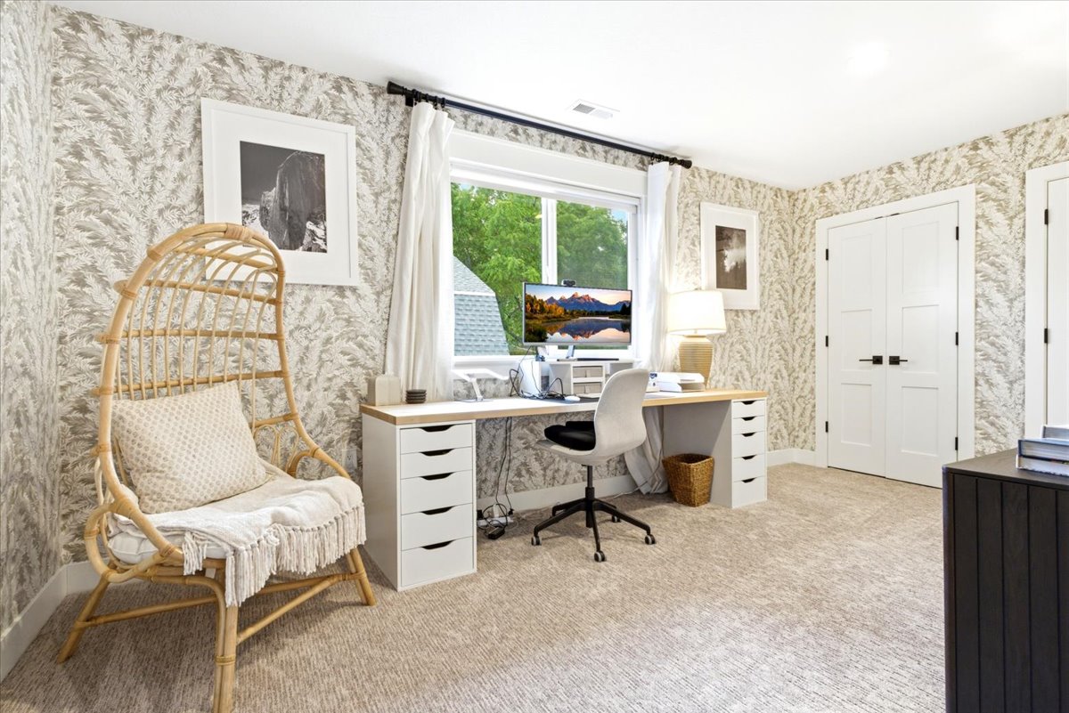 Spacious room with patterned wallpaper, large window, and light-tone carpet flooring