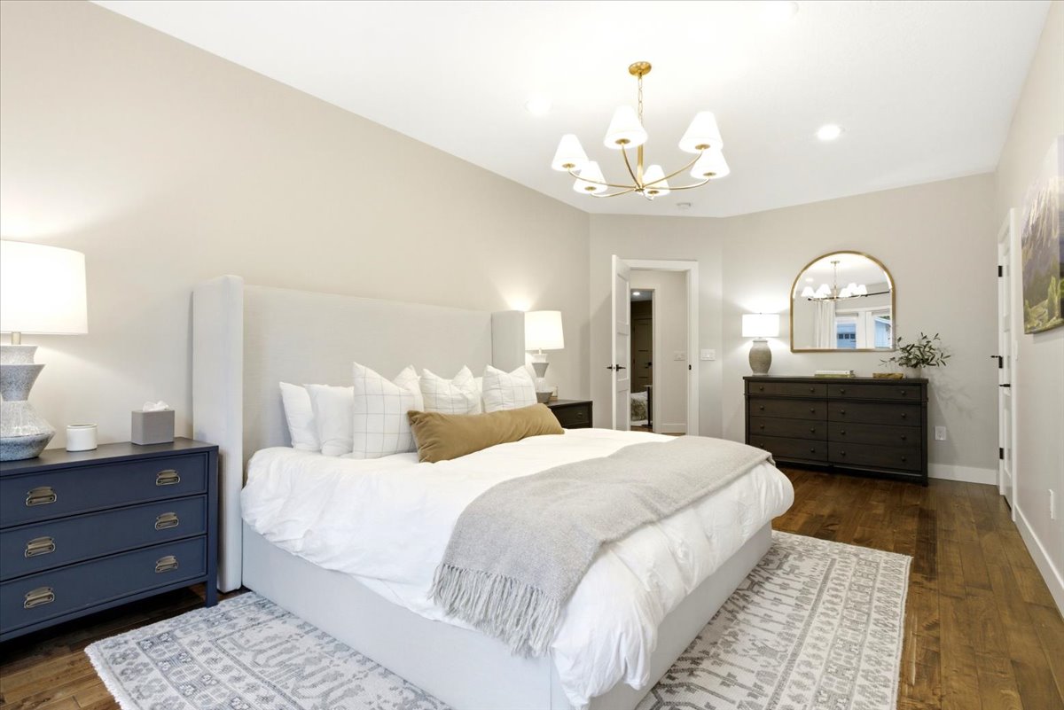 Spacious bedroom featuring wood-finish flooring, recessed lighting, and a contemporary chandelier