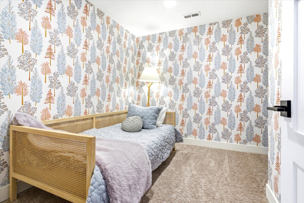Carpeted room with patterned wall covering, white trim, and a white door with a matte black lever handle