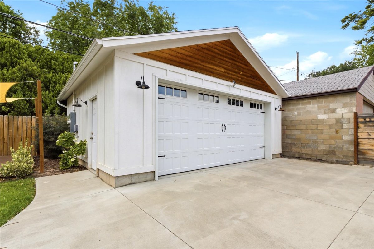 Detached garage featuring a white paneled door with upper window lights, board and batten siding, and a warm wood-finish gable accent