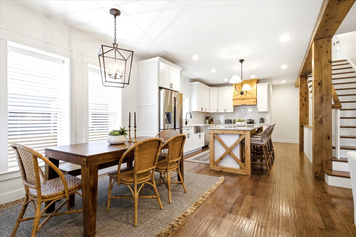 Open-concept dining area and kitchen featuring wood-finish flooring, white cabinetry, a kitchen island with a light-toned countertop, and recessed lighting