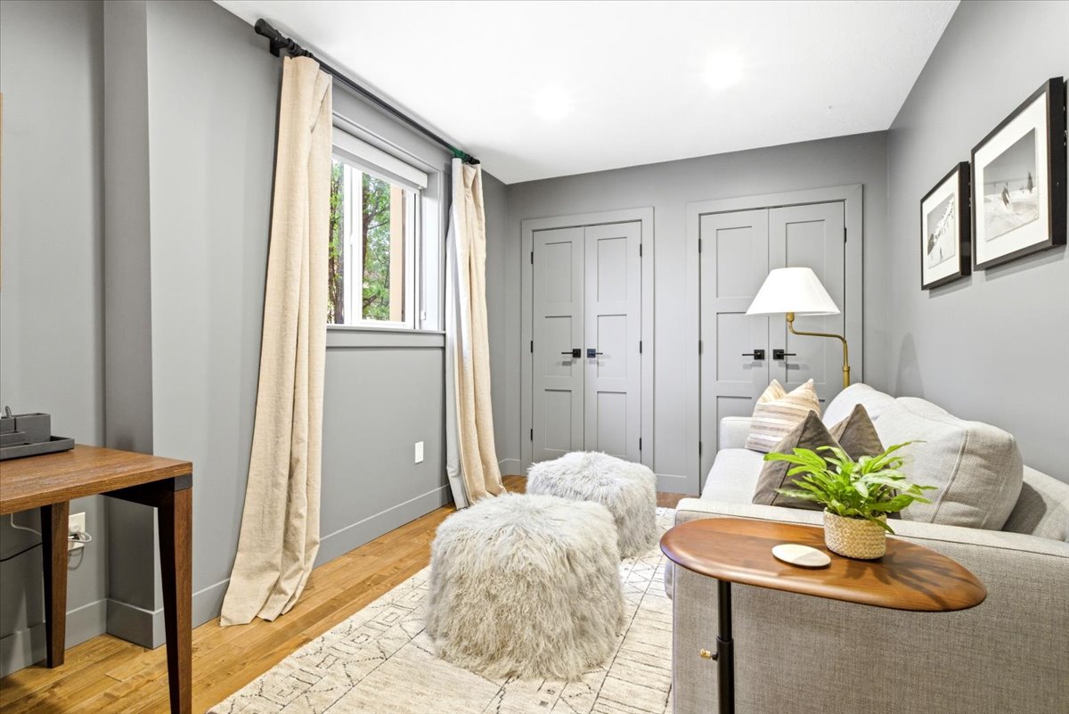 Interior room featuring light gray walls, wood-finish flooring, recessed lighting, and two panel doors with black hardware