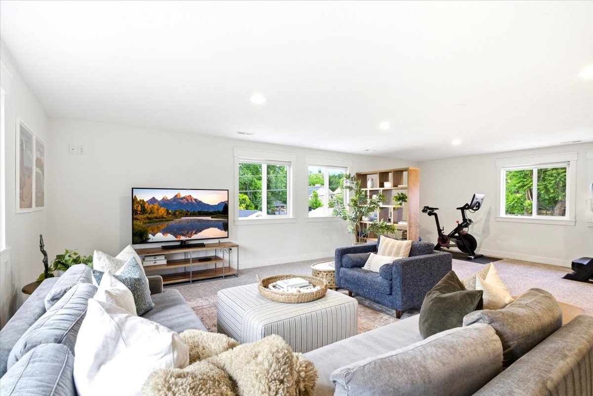 Spacious interior room featuring light-toned walls, recessed lighting, and multiple windows with white trim
